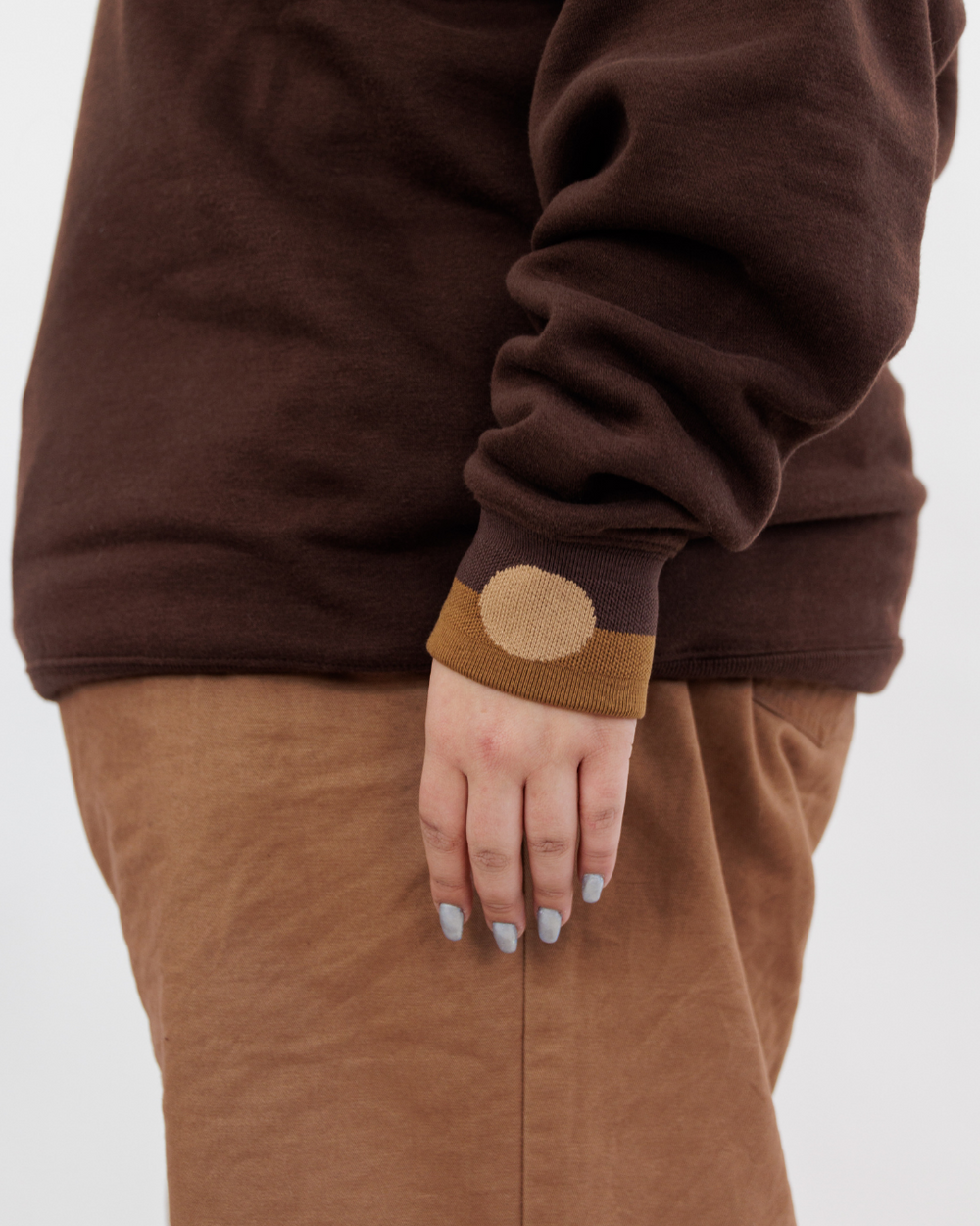 Clothing The Gaps. Chocolate Crew Jumper. Brown chocolate crew neck jumper. With tonal lighter brown 'Clothing the gaps' and the word 'Narrm' embroidered on the front of crewneck.' Wear your values' is also embroidered small on the back of the crew with the same light brown tonal colour. The wrist cuffs of the crew have a woven tonal brown aboriginal flag on them. 