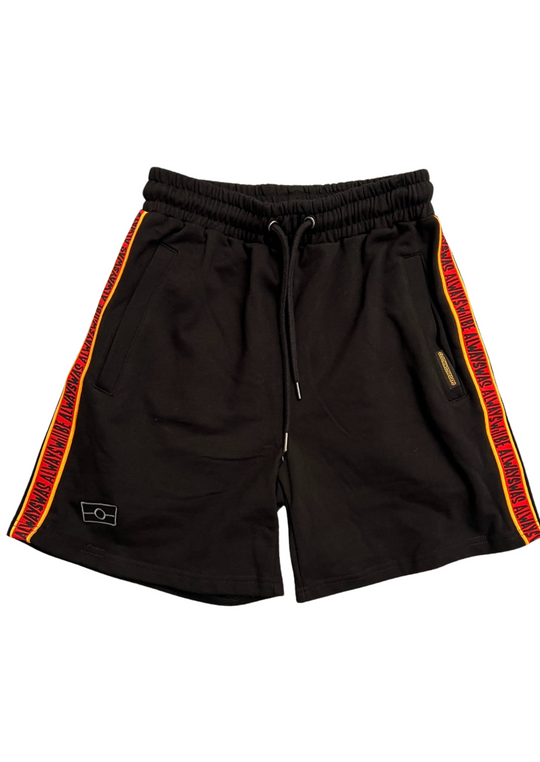 Clothing the Gaps. Black cotton shorts. With black drawstrings. Embroiled black outlined aboriginal flag in corner. Black 'always was always will be' text on a red background with a yellow trim. In a cotton tape strip going down both sides of shorts.