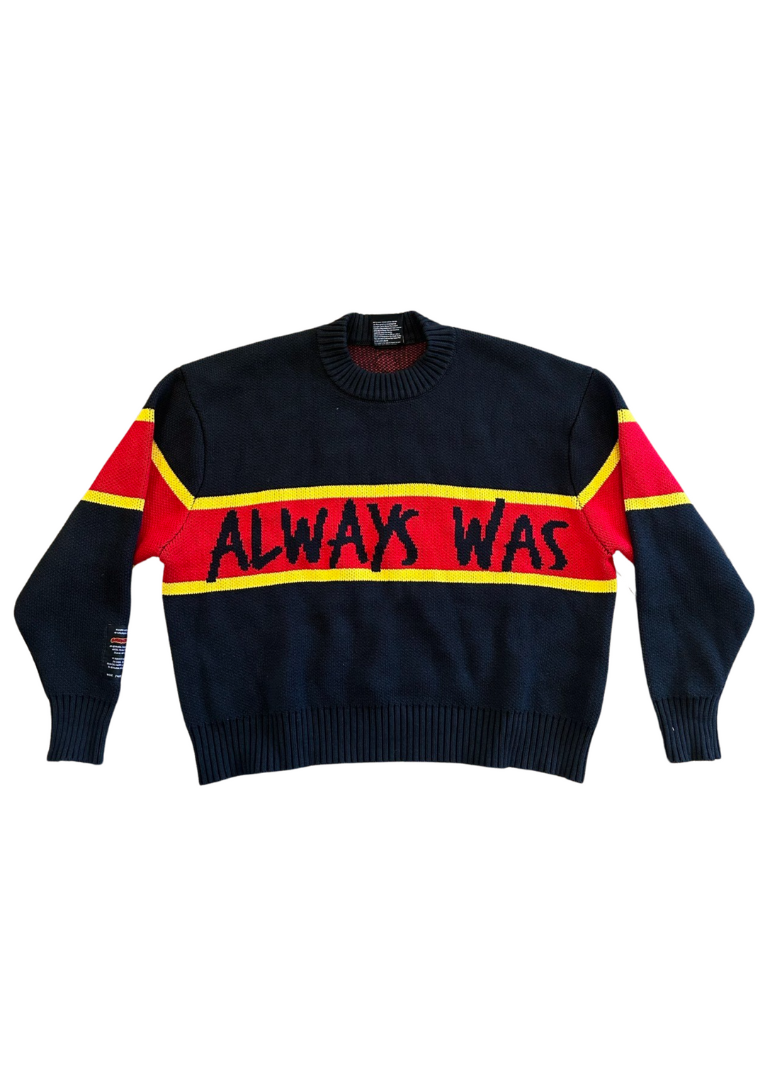 Clothing The Gaps. Power Knit Jumper. Red, black and yellow colorway heavyweight 100% cotton oversized boxy fit. Black base with thick yellow top and bottom lines and red fill in mid section of jumper that flows into same pattern on sleeves. In red section on front of jumper in bold hand-written type capital text reads 'Always was' and on back in same text 'Always will be.' With black knitted cuffs and waistband.