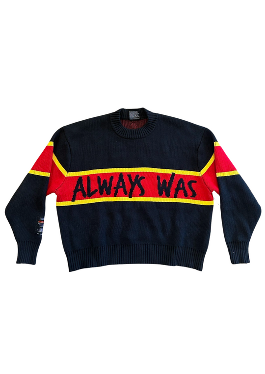 Clothing The Gaps. Power Knit Jumper. Red, black and yellow colorway heavyweight 100% cotton oversized boxy fit. Black base with thick yellow top and bottom lines and red fill in mid section of jumper that flows into same pattern on sleeves. In red section on front of jumper in bold hand-written type capital text reads 'Always was' and on back in same text 'Always will be.' With black knitted cuffs and waistband.