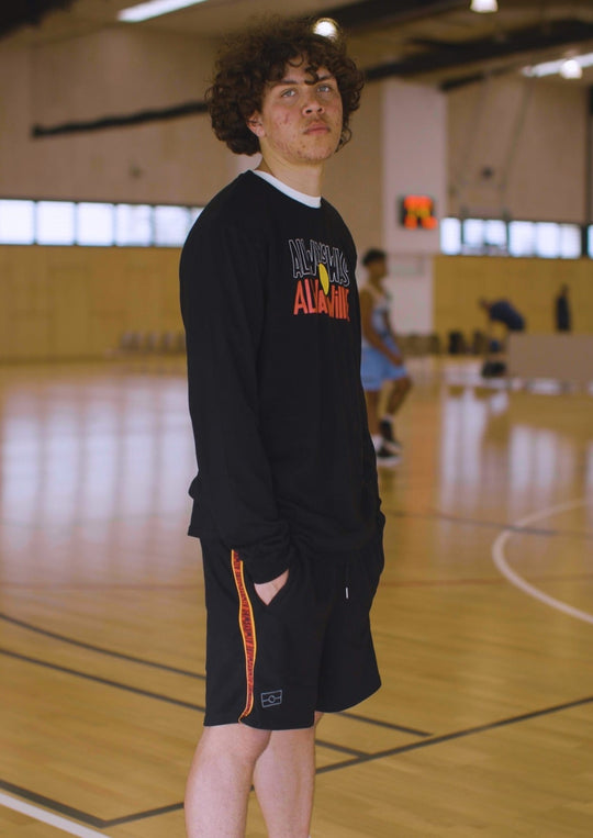 Clothing the Gaps. Black cotton shorts. With black drawstrings. Embroiled black outlined aboriginal flag in corner. Black 'always was always will be' text on a red background with a yellow trim. In a cotton tape strip going down both sides of shorts.