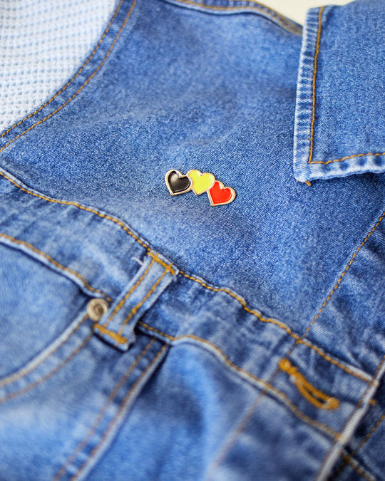 Clothing The Gaps. Blak Luv Pin. 3 hearts Black, yellow and red the colours of the Aboriginal flag. with a skinny gold outline. With a gold backing and pin back.