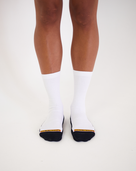 Clothing The Gaps. White Empty Flag Socks. Long white socks with black Aboriginal flag outline on back. Black on bottom of sock to hide dirt. Clothing The Gaps written above toe area.