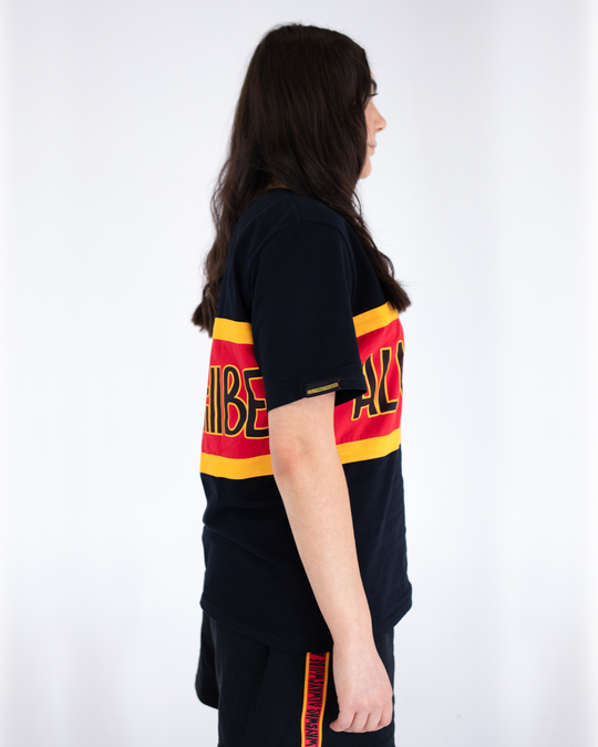 Clothing The Gaps. Power Rugby Tee. Red, black and yellow colorway. Black base tee with thick yellow top and bottom lines and red fill in mid section of jumper with big bold black text with a yellow outline in red section. Reading 'Always was' on front and on back in same text 'Always will be.'