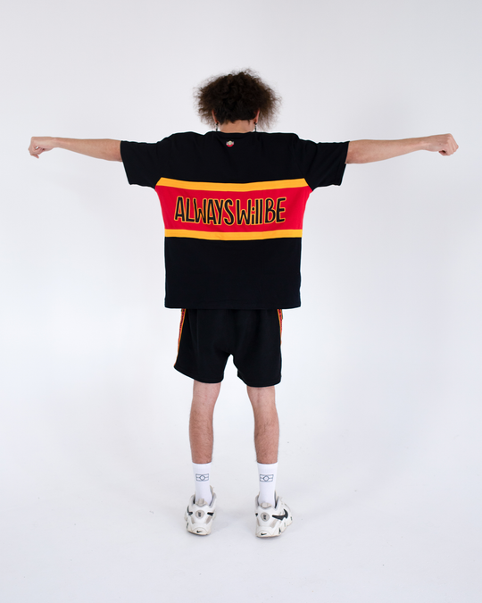 Clothing The Gaps. Power Rugby Tee. Red, black and yellow colorway. Black base tee with thick yellow top and bottom lines and red fill in mid section of jumper with big bold black text with a yellow outline in red section. Reading 'Always was' on front and on back in same text 'Always will be.' 