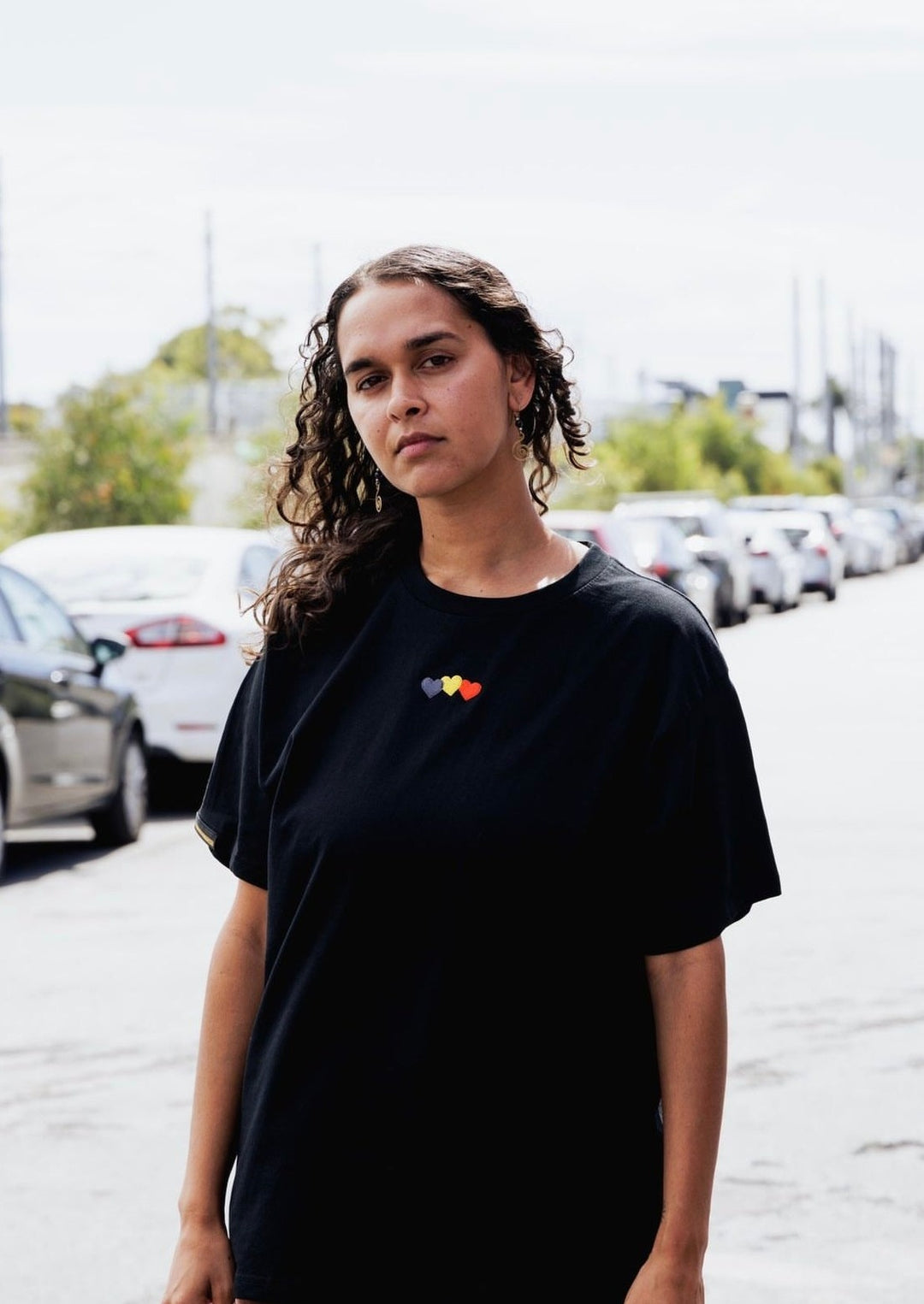 Clothing The Gaps. Blak Luv Tee. All black tee with  Red, black and yellow hearts embroiled on front the colours of the aboriginal flag.