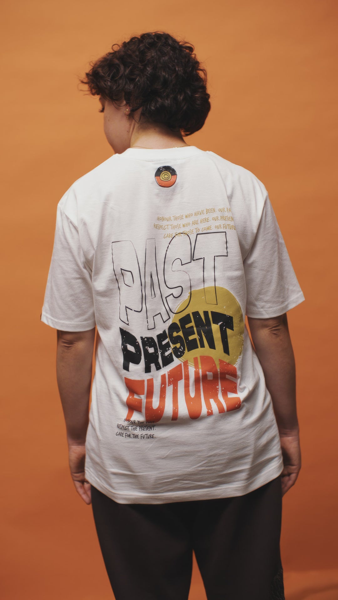 Clothing The Gaps. Past Present Future Tee. White tee with a small 'Past, Present, Future' pocket square on the front and large 'Past, Present , Future screen print back Black white and red with a yellow sun behind.