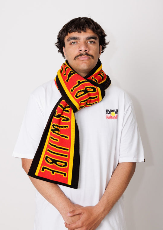 Clothing The Gaps. Power Scarf. High quality thick scarf with black bold text with a yellow outline reading 'always was always will be.' Text is on a red background with a yellow thin line then thick black trim. 