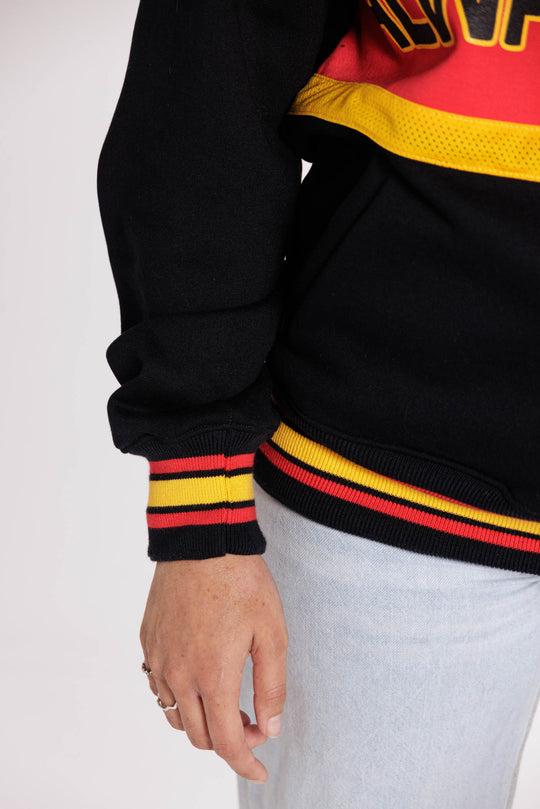 Clothing The Gaps. Power Rugby Jumper V3. Quarter zip Red, black and yellow colorway. Black base with thick yellow mesh top and bottom lines and red fill in mid section of jumper with big bold black text with a yellow outline in red section. Reading 'Always was' on front and on back in same text 'Always will be.' Kangaroo pockets. Custom knitted red, black and yellow striped retro bands on wrists and bottom of rugby jumper.