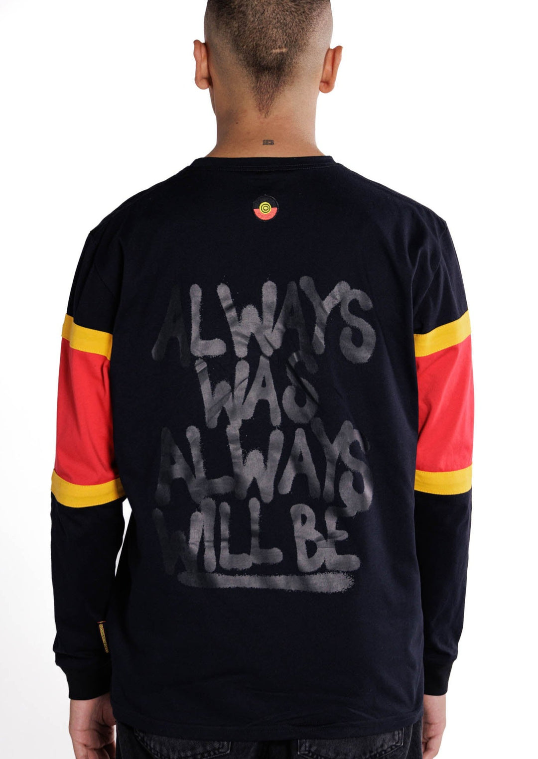 Clothing The Gaps. Black Power Longsleeve. Red, black and yellow sleeves. Aboriginal flag outline embroidered in black on the front. On the back of the hoodie a screen printed powerful Aboriginal chant 'Always Was, Always Will Be' looks like it has been sprayed on with a black spray can! The Clothing the Gaps circle logo patch of red, black and yellow just below neckline centred on upper back.
