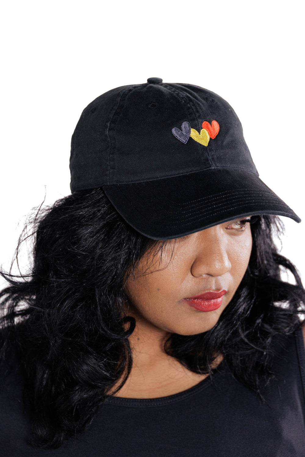 Clothing The Gaps. Blak Luv Cap. All black with  Red, black and yellow hearts embroidered on front. Clothing The Gaps embroidered on back in black stitching. Adjustable clip strap on back with silver clip featuring Clothing The Gaps logo.