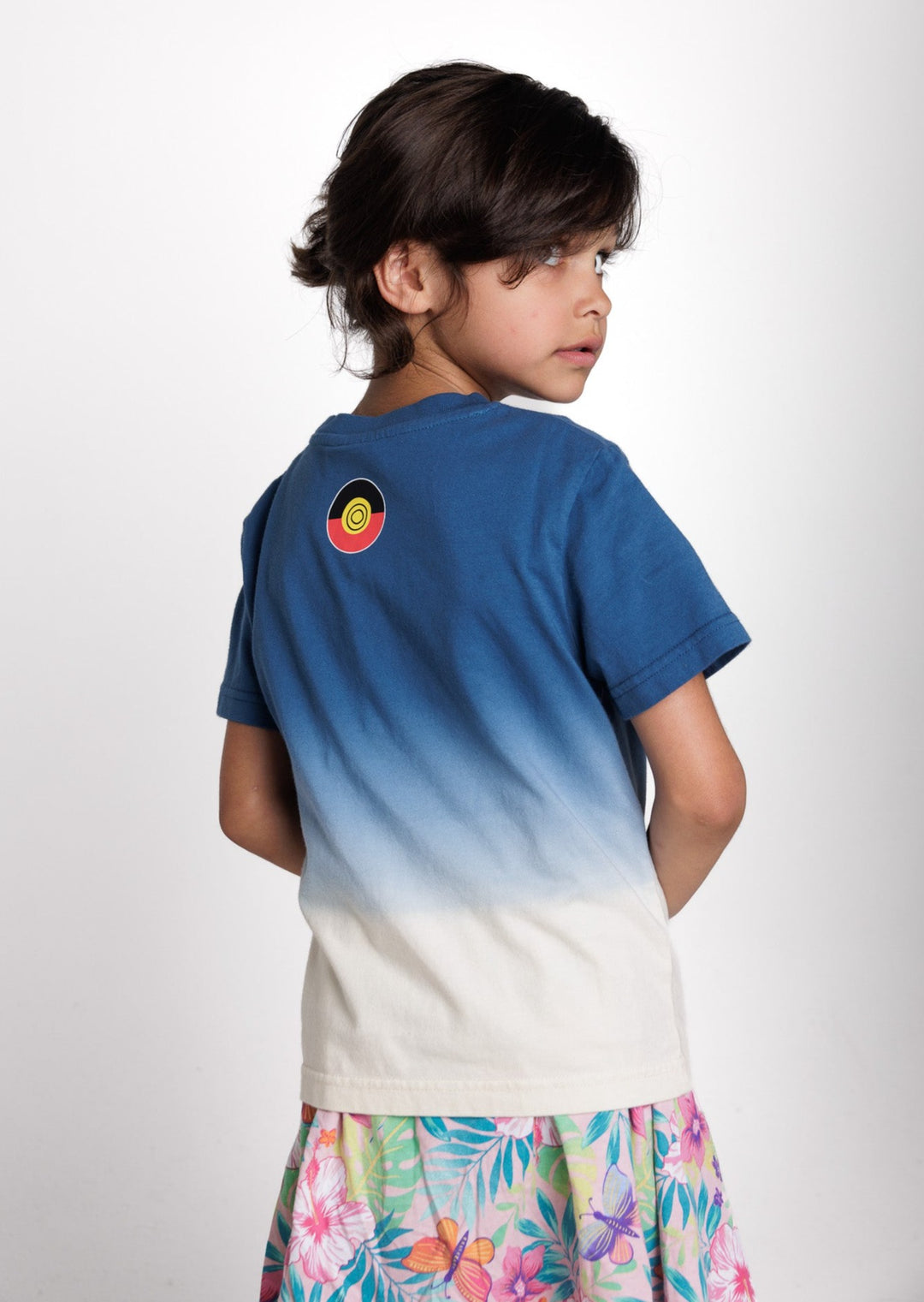 Clothing The Gaps. Kids Dip Dye 'Always Was, Always Will Be' Tee. Blue died t-shirt that fades down from the top of t-shirt to lighter blues then a cream white. With a Black, yellow and red 'always was always will be' text screen printed in left corner pocket sized.