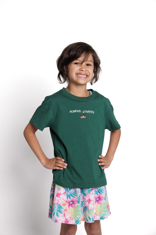 Clothing The Gaps. Kids Handwritten Honour Country Tee. Forrest green T-shirt with 'Honour Country' across chest in handwritten white text and coloured Aboriginal flag small underneath. On Back of tee white hand-writen style text 'Honour and respect Aboriginal and Torres Strait Islander people as the rightful custodians of country.' Circling 'respect' underlining 'custodians' and highlighting 'rightful' in a black colour. Outlined 'bunjil' eagle in bottom right corner.'        