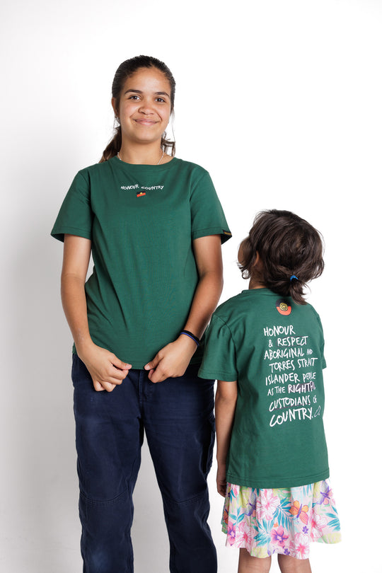 Clothing The Gaps. Kids Handwritten Honour Country Tee. Forrest green T-shirt with 'Honour Country' across chest in handwritten white text and coloured Aboriginal flag small underneath. On Back of tee white hand-writen style text 'Honour and respect Aboriginal and Torres Strait Islander people as the rightful custodians of country.' Circling 'respect' underlining 'custodians' and highlighting 'rightful' in a black colour. Outlined 'bunjil' eagle in bottom right corner.'        