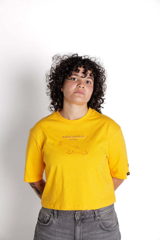 Clothing The Gaps. Bunjil Sun Crop Tee. Yellow cropped boxy fit t-shirt with Bunjil, a well-known wedge tailed eagle who is the spiritual creator and protector of the Kulin Nation embroidered  da darker contrasting yellow. On top of the embroidered Bunjil is 'Clothing the gaps' embroidered in the same colour as-well as the word Narrm which Wurundjeri refer to the scrubland (Narrm) in the Greater Melbourne CBD area, and Boonwurrung people use this word to refer 'The Bay,' referencing Port Phillip Bay area. 