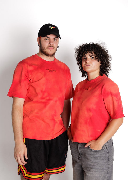 Clothing The Gaps. First Sunrise Tee. Red tee with an acid wash tie died look with varying darker red, lighter red and blood orange colours. Featuring embroidered  'Clothing The Gaps' in a darker contrasting red and 'Narrm,' underneath in the same darker red. 