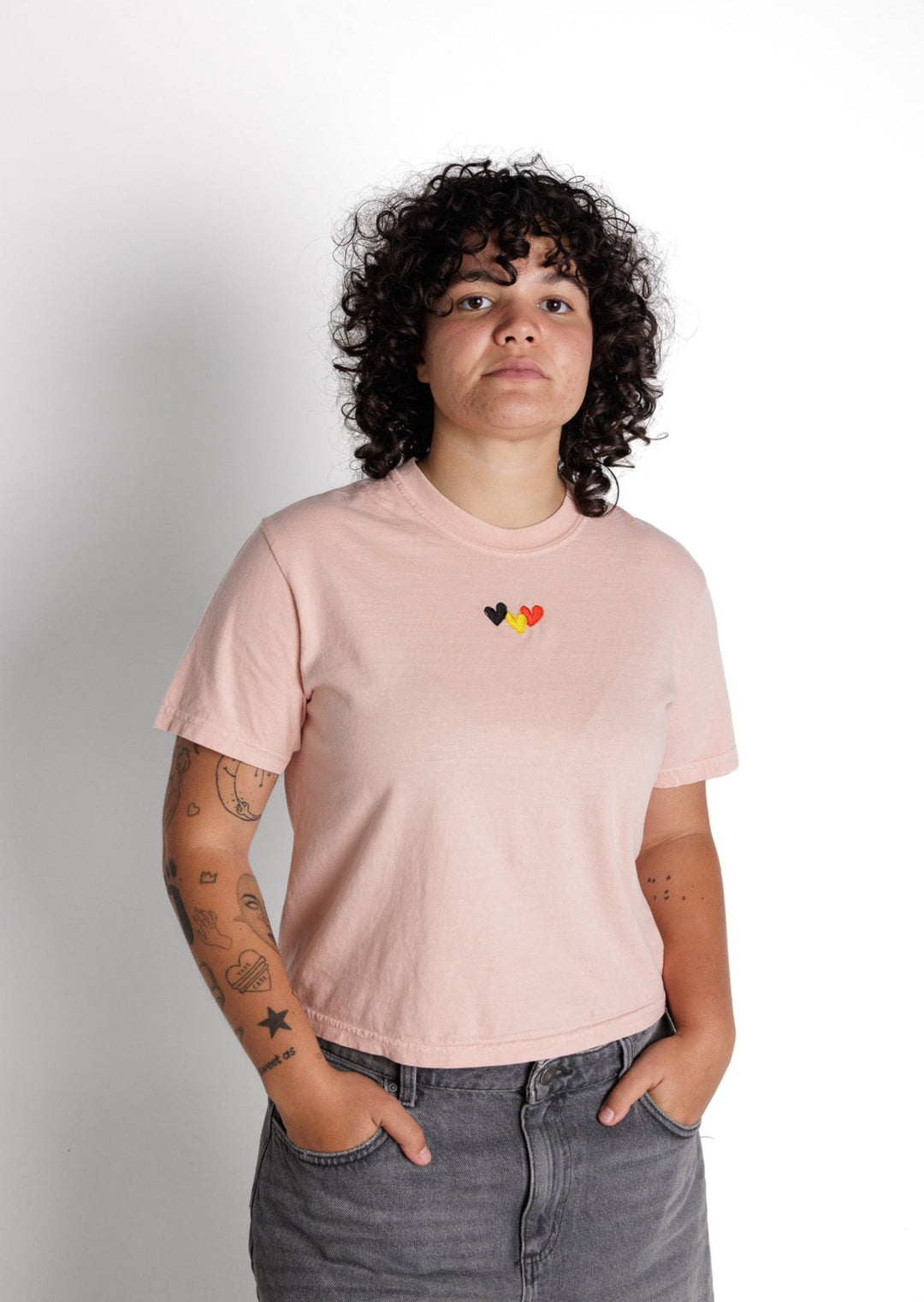 Clothing The Gaps.Peachy Blak Luv Crop Tee. peachy pink cropped tee with  Red, black and yellow hearts embroiled on front the colours of the aboriginal flag.