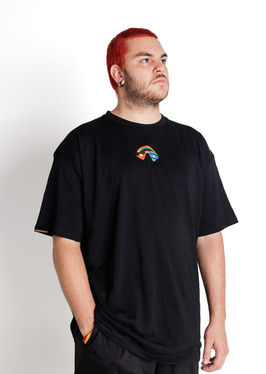Clothing The Gaps. Blak Rainbow Luv Crop. All black boxy crop tee with  a heart featuring the Aboriginal flag at the start of a rainbow and at the end of the rainbow the Torres Strait Islander flag. The rainbow includes the colours from the progress pride flag. Show your pride or support for First Nations LGBTQIAS&B+ Community.