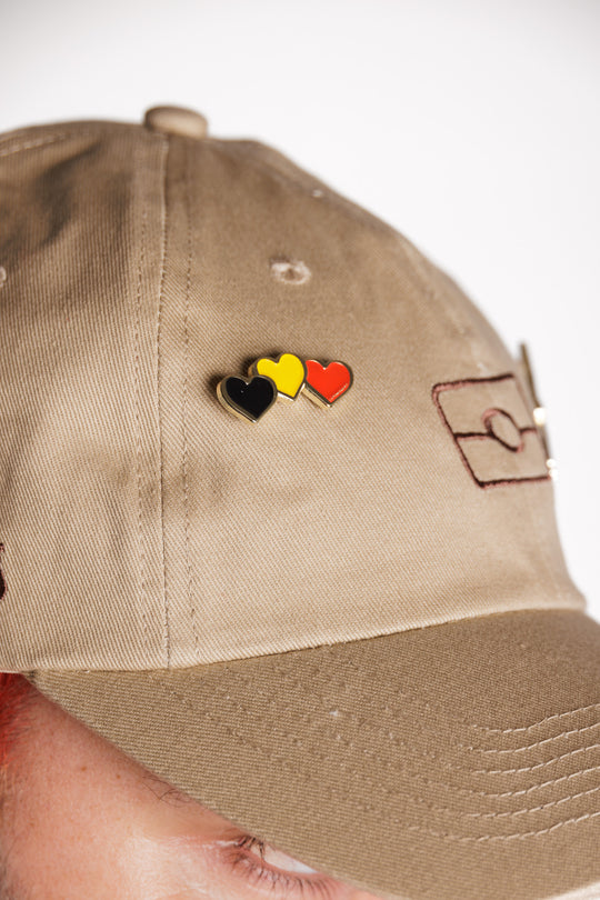 Clothing The Gaps. Blak Luv Pin. 3 hearts Black, yellow and red the colours of the Aboriginal flag. with a skinny gold outline. With a gold backing and pin back.