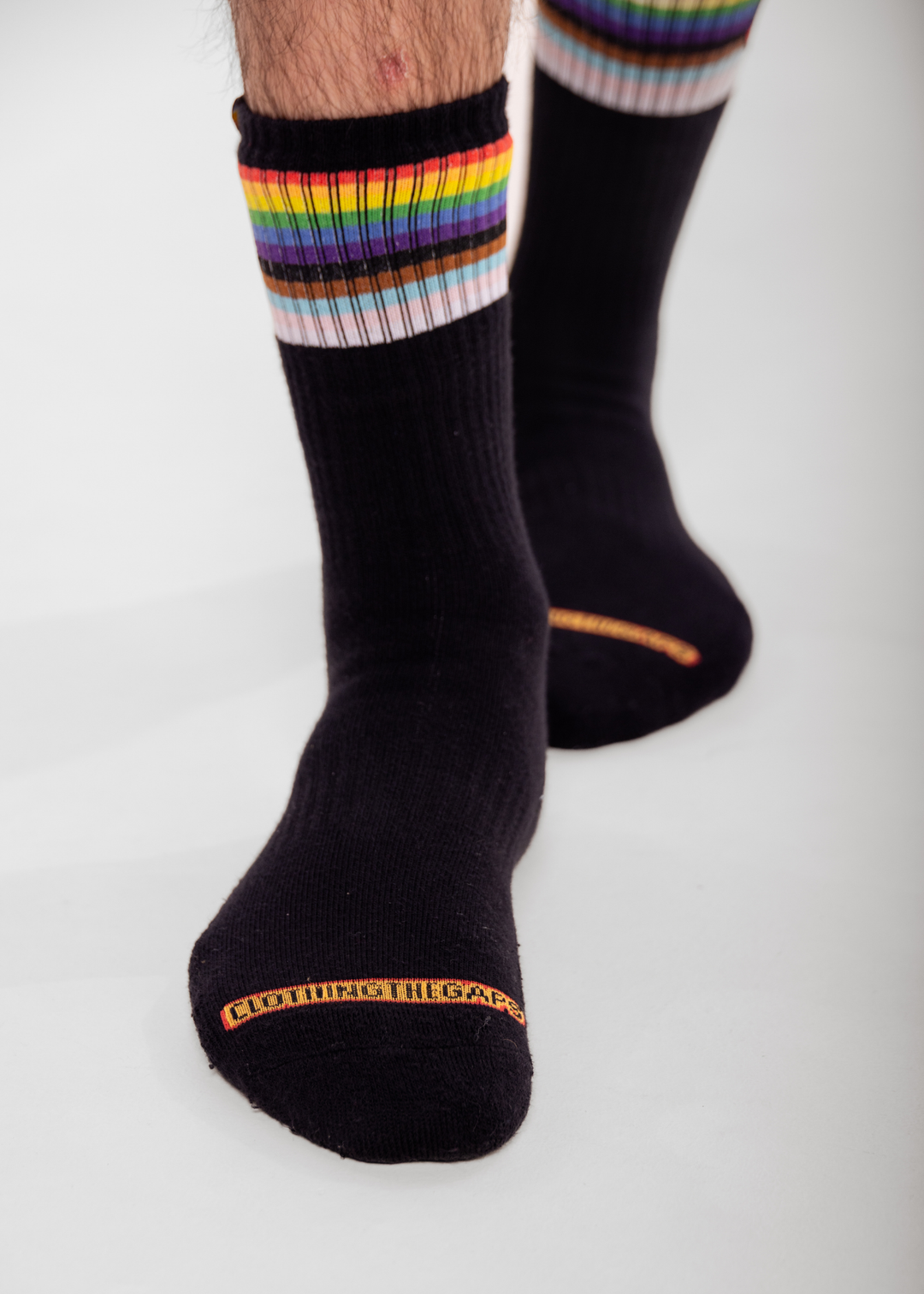 Black socks with rainbow striped cuffs on a white background CLothing The Gaps branding on toes