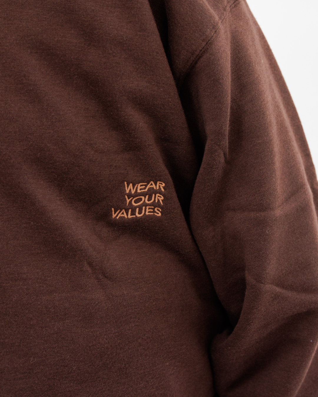 Clothing The Gaps. Chocolate Crew Jumper. Brown chocolate crew neck jumper. With tonal lighter brown 'Clothing the gaps' and the word 'Narrm' embroidered on the front of crewneck.' Wear your values' is also embroidered small on the back of the crew with the same light brown tonal colour. The wrist cuffs of the crew have a woven tonal brown aboriginal flag on them. 