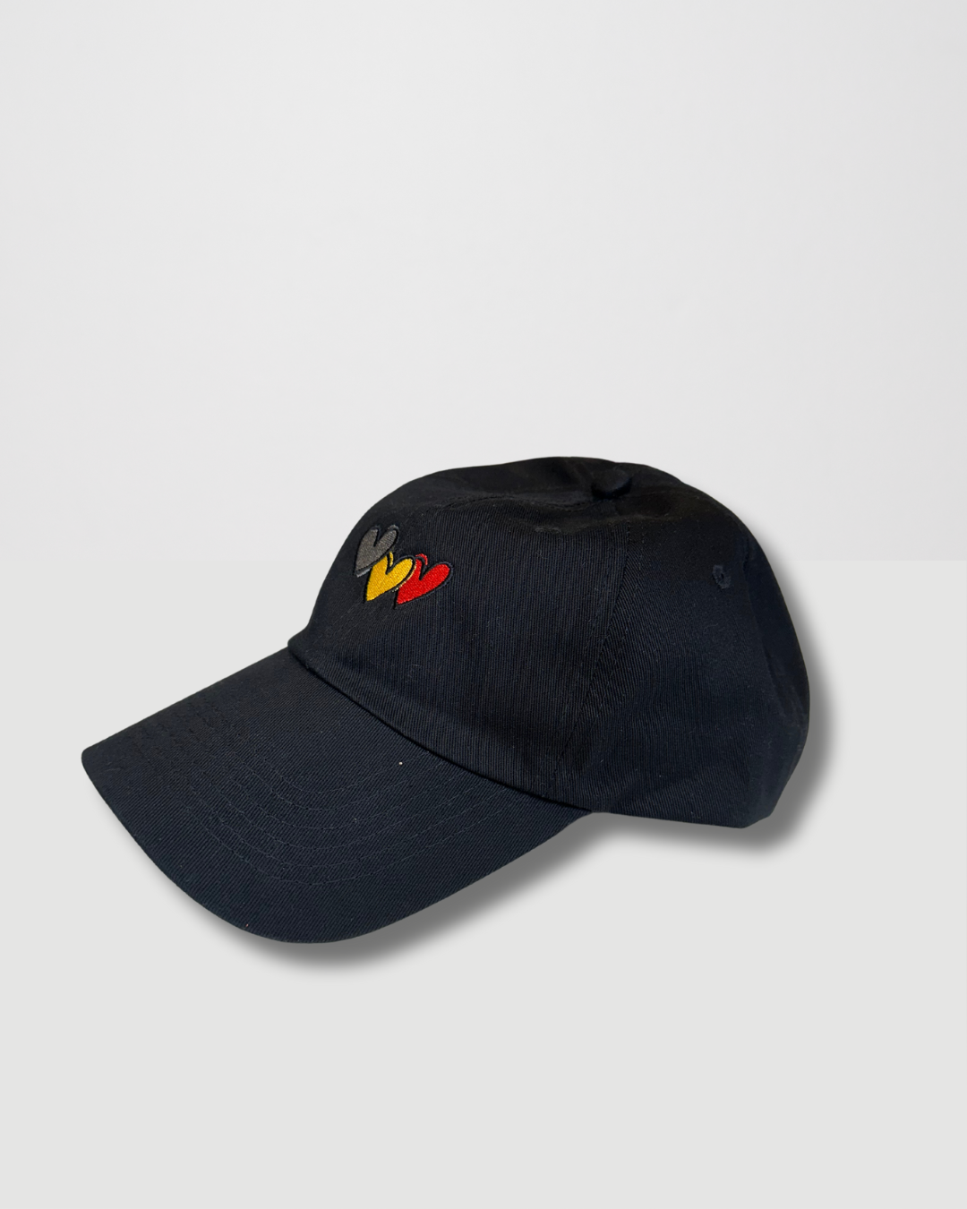 Clothing The Gaps. Blak Luv Cap. All black with  Red, black and yellow hearts embroidered on front. Clothing The Gaps embroidered on back in black stitching. Adjustable clip strap on back with silver clip featuring Clothing The Gaps logo.