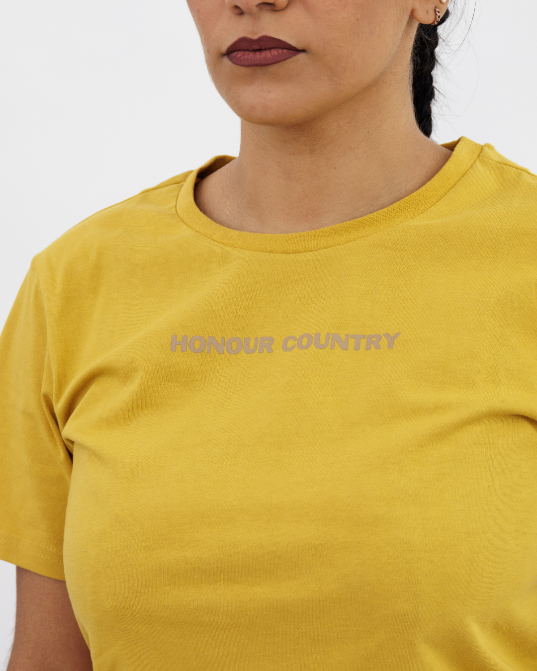 Clothing The Gaps. Kids Mustard Honour Country Tee. Mustard yellow t-shirt with screen printed bold capital text 'Honour and respect Aboriginal and Torres Strait Islander people as the rightful custodians of country.' The word 'Honour country' on the front in the same text and contrasting colour.