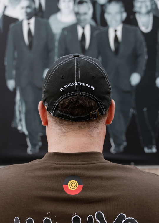 Black cap with Clothing The Gaps embroidered in white across the back and a brass adjustable strap