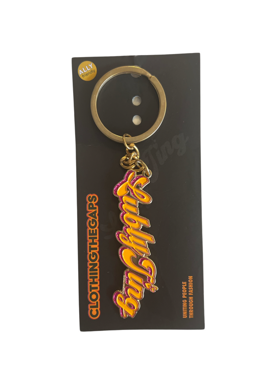Clothing The Gaps. Lubly Ting Keyring. Yellow 'Lubly Ting' cursive text with a pink glitter enamel fill outline. Attached to a gold chain and keyring.