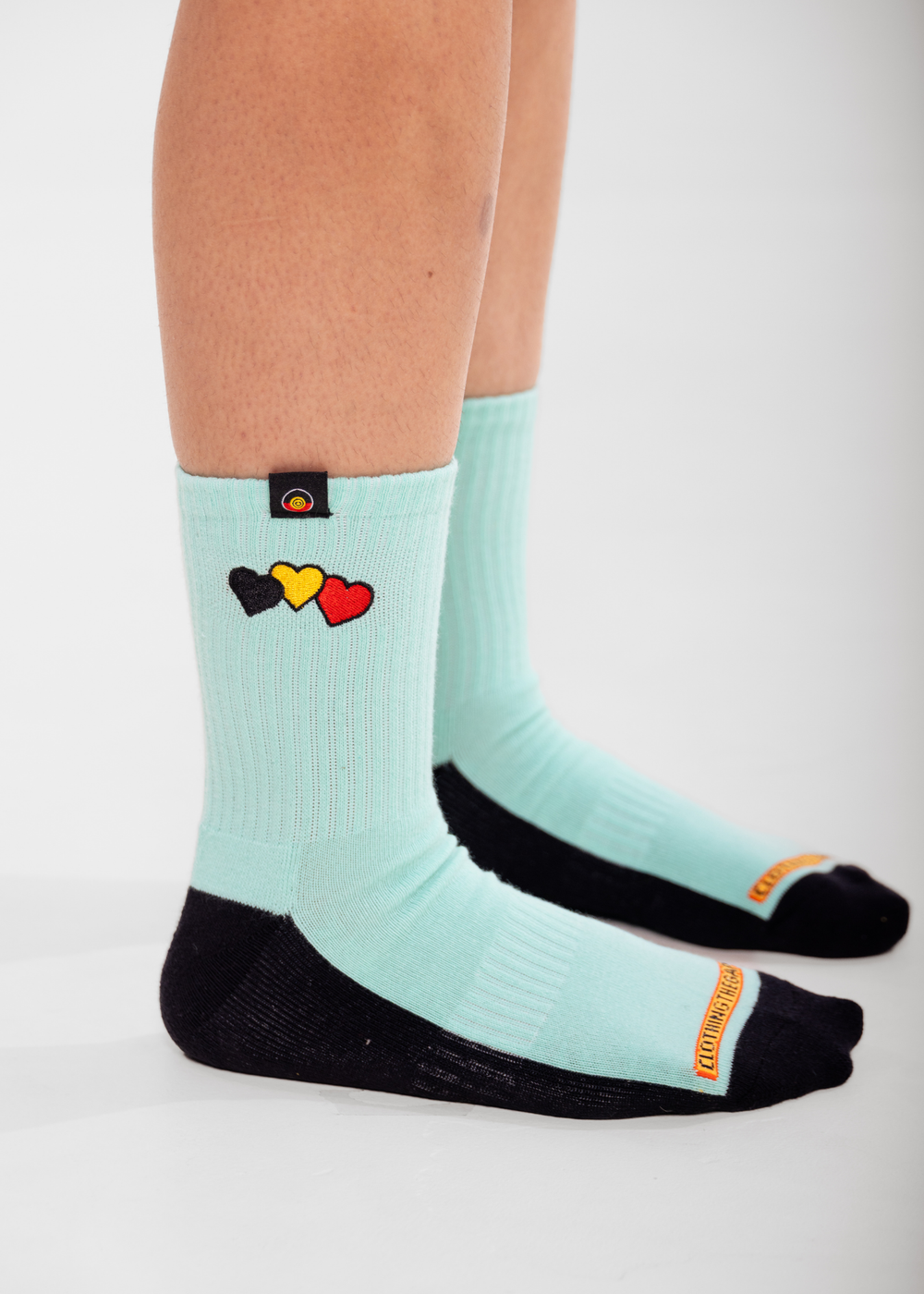 Light blue socks with colorful heart design worn by a person on a white background