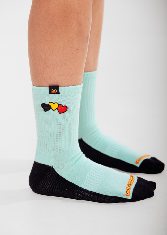Light blue socks with colorful heart design worn by a person on a white background