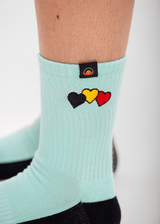 Light blue sock with colorful heart designs and a  Clothing The Gaps brand logo on a white background