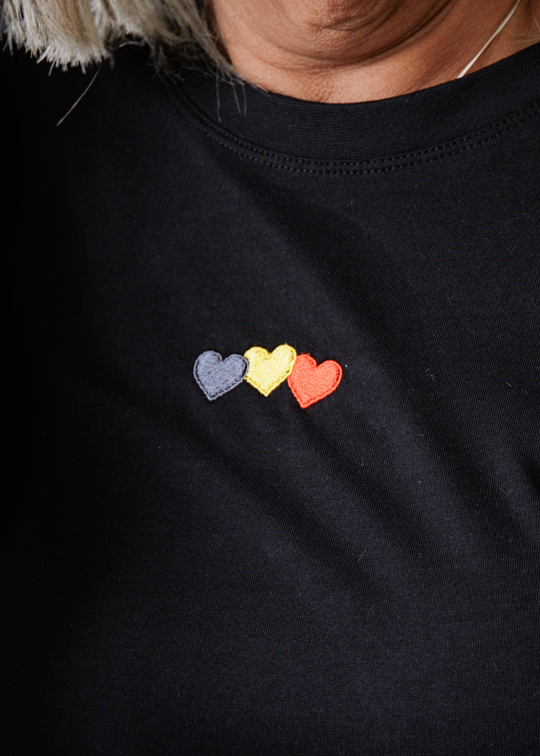 Black sweatshirt with black yellow and red heart shapes on a person wearing it.