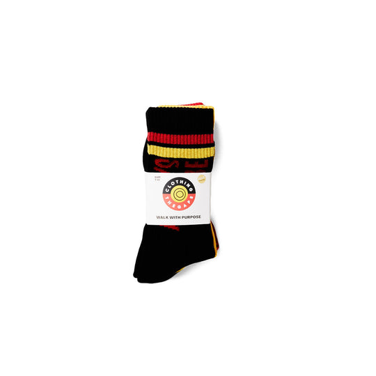 Clothing The Gaps. Power Socks 3 pack. 3 pack red, black and yellow thick cotton socks. Pair 1 Black base sock with 'Always was' on one side of sock and 'Always will be' on other side with red capital text and red and yellow band near top of sock. Pair 2 Red base sock with same text but in yellow and black. With yellow band near top of sock. Pair 3 yellow base sock with same text but in black. With black and red band near top of sock.