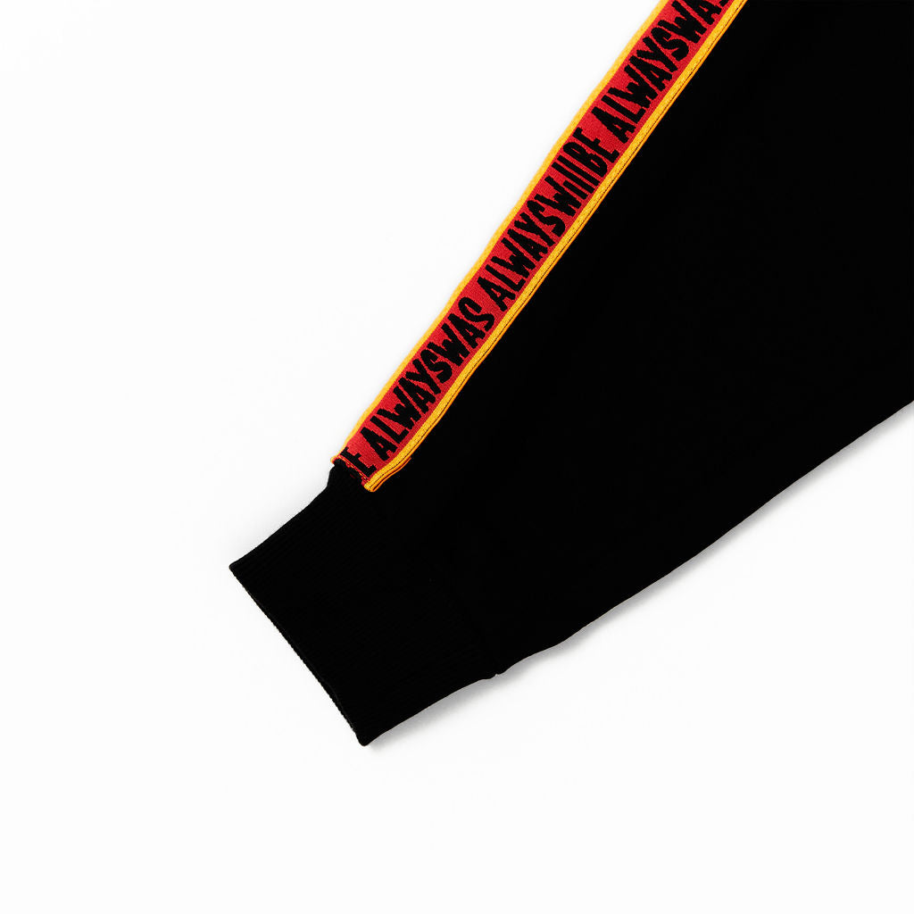 Clothing the Gaps. KIDS 'Always Was, Always Will Be' Track Pants. Black cotton Pants. With black drawstrings. Elastic cuts and waistband. Embroiled Clothing The Gaps logo. Black 'always was always will be' text on a red background with a yellow trim. In a cotton tape strip going down both sides of pants. 