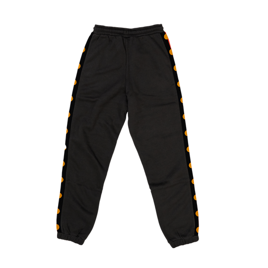 Clothing The Gaps. Charcoal Flag Track Pants. Charcoal dark grey track pants with Aboriginal flag tape down the sides. Has a elastic waist with charcoal grey draw strings and cuffed ankles.