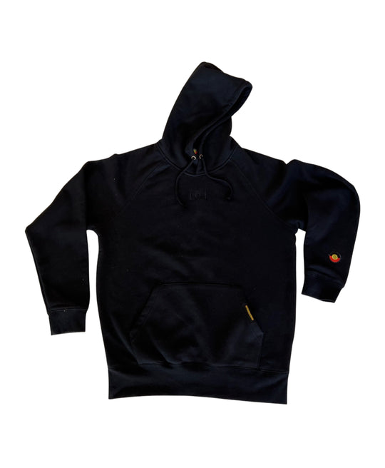 Clothing The Gaps. Black hoodie with Aboriginal flag outline embroidered in black on the front. On the back of the hoodie a powerful Aboriginal chant 'Always Was, Always Will Be' looks like it has been sprayed on with a black spray can! The Clothing the Gaps circle logo patch provides a sneaky little pop of red, black and yellow on the sleeve.