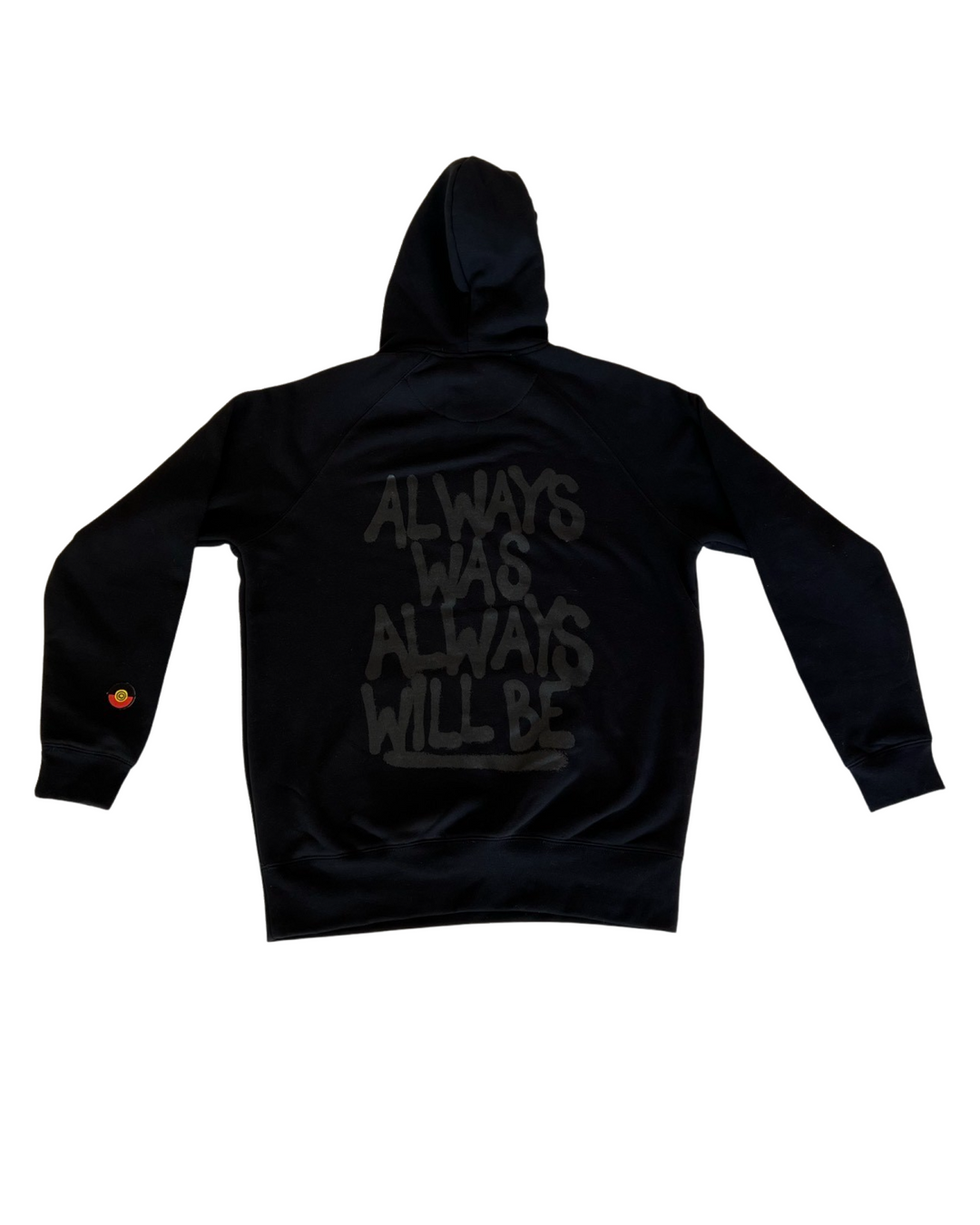 Clothing The Gaps. Black hoodie with Aboriginal flag outline embroidered in black on the front. On the back of the hoodie a powerful Aboriginal chant 'Always Was, Always Will Be' looks like it has been sprayed on with a black spray can! The Clothing the Gaps circle logo patch provides a sneaky little pop of red, black and yellow on the sleeve.