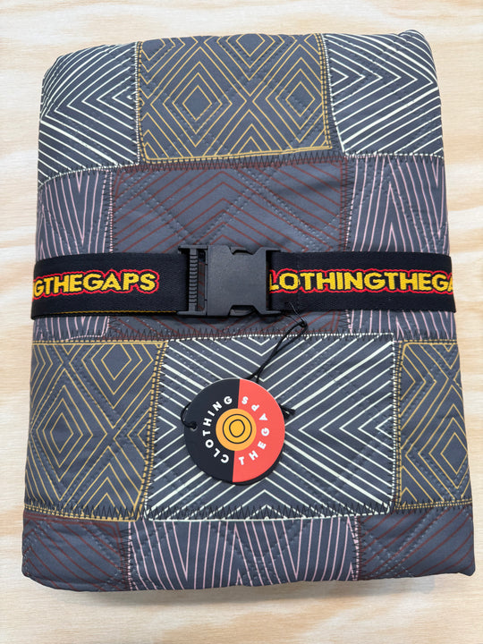 Folded fabric with geometric pattern and 'clothing The Gaps' branding on a light wooden surface