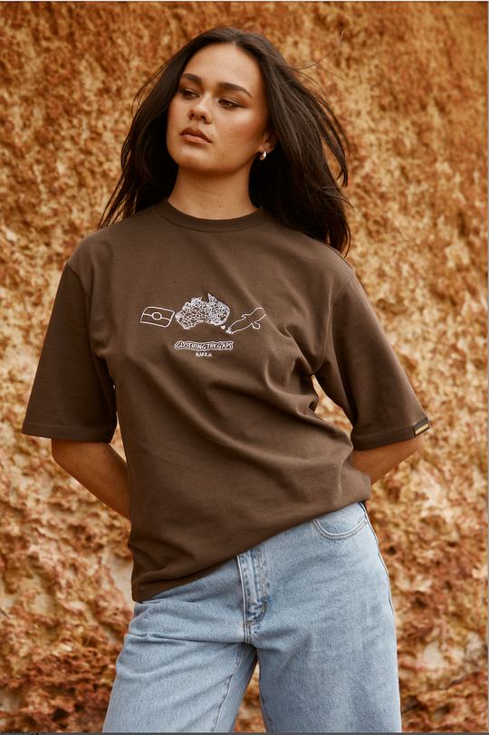 Woman wearing a Clothing The Gaps brown t-shirt with a logo against a textured brown background
