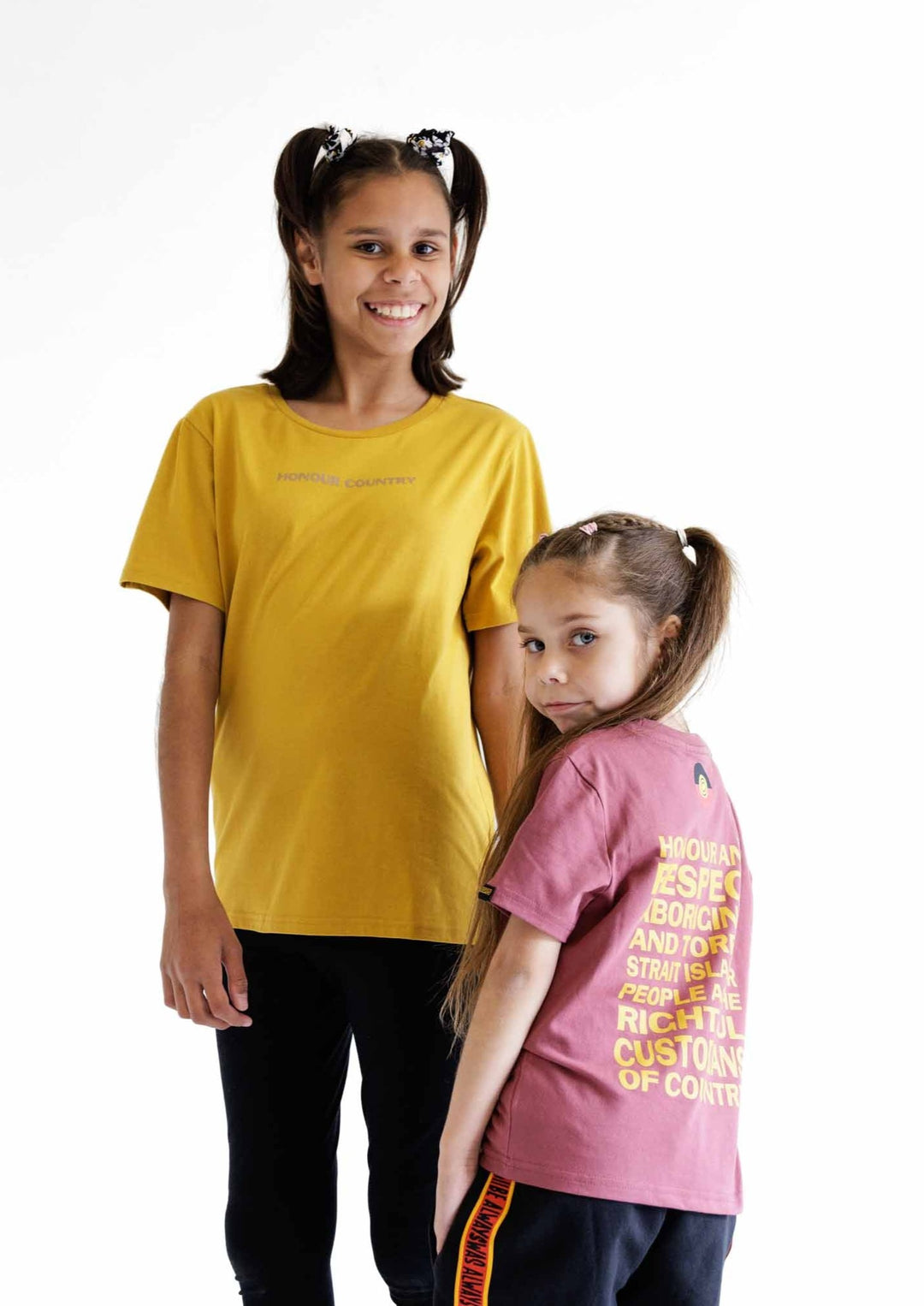 Clothing The Gaps. Kids Mustard Honour Country Tee. Mustard yellow t-shirt with screen printed bold capital text 'Honour and respect Aboriginal and Torres Strait Islander people as the rightful custodians of country.' The word 'Honour country' on the front in the same text and contrasting colour.