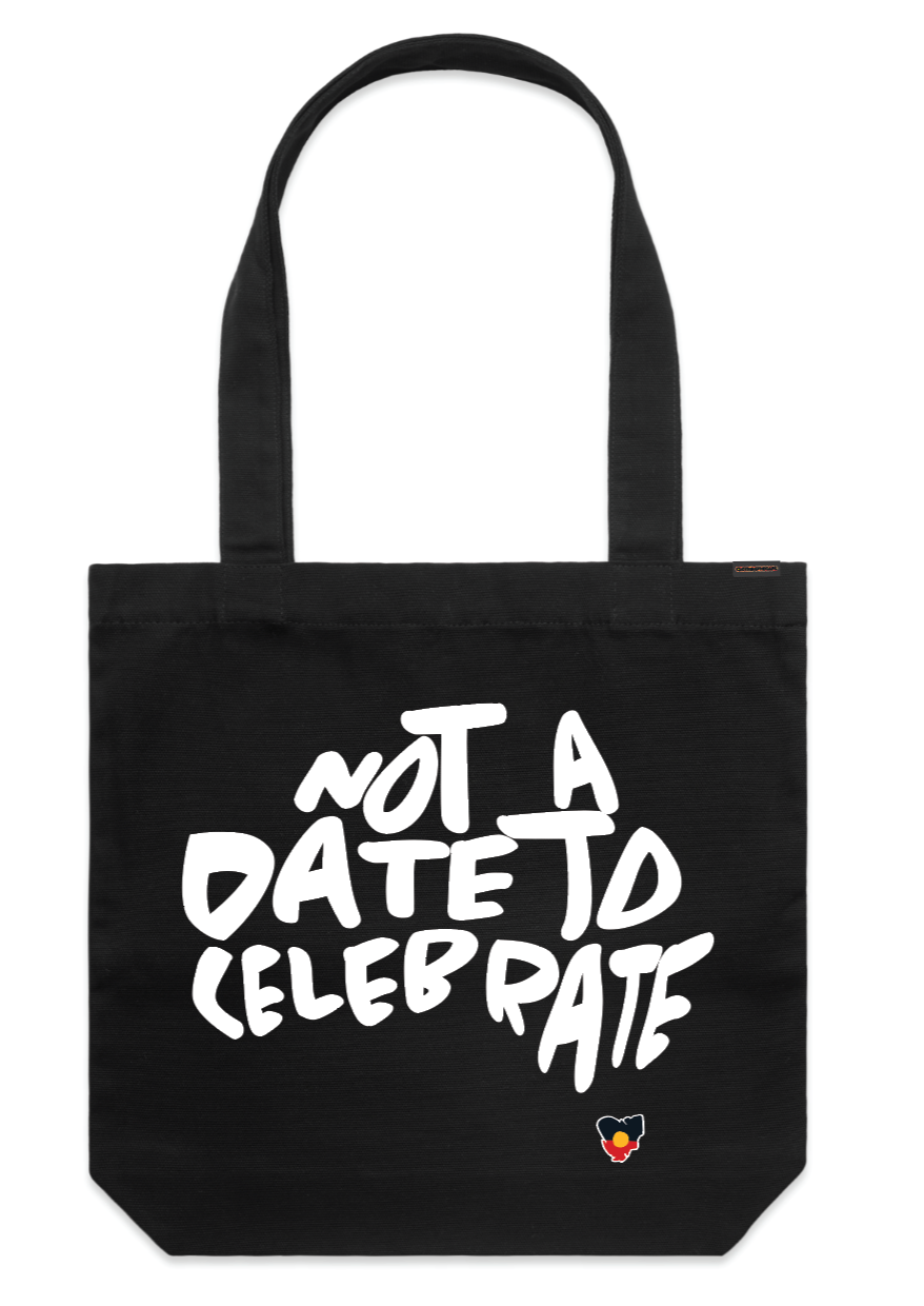 Clothing The Gaps. Not A Date To Celebrate Tote Bag. Black tote  bag with screen printed 'Not A Date To Celebrate' white text in the shape of Australia and the Aboriginal flag in the shape of Tasmania screen print is big on the front of bag.