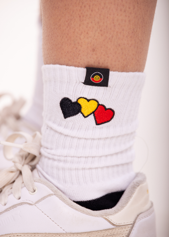 White Clothing The Gaps sock with colorful heart design worn with a white sneaker on a light background