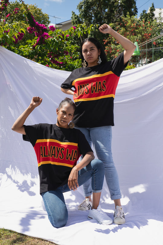 Clothing The Gaps. Power Rugby Tee. Red, black and yellow colorway. Black base tee with thick yellow top and bottom lines and red fill in mid section of jumper with big bold black text with a yellow outline in red section. Reading 'Always was' on front and on back in same text 'Always will be.' 