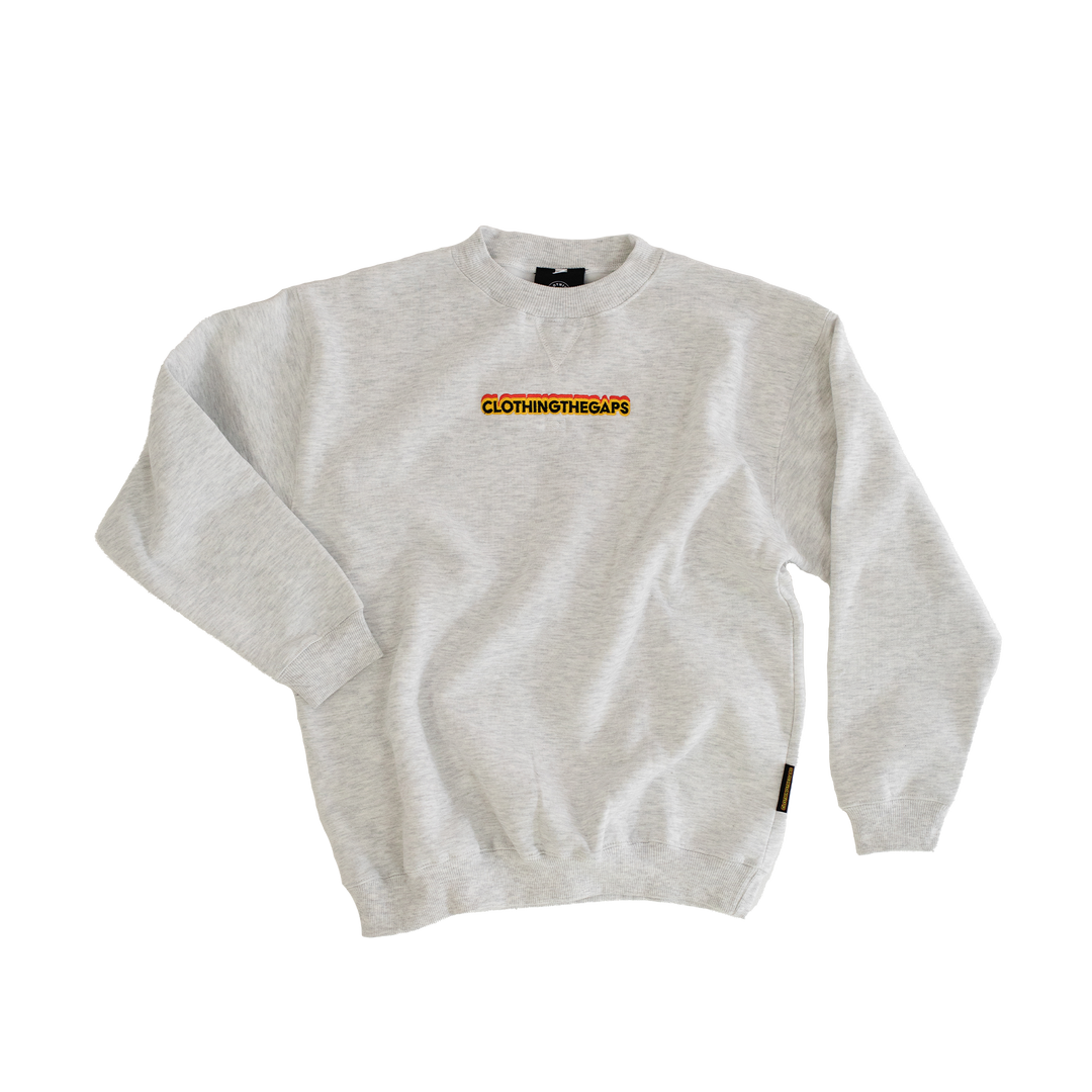 Clothing The Gaps. Classic Crew Jumper. This light grey crew jumper features a minimalist front embroidery piece proudly showcasing the words "Clothing The Gaps" in black with a yellow and red outline. Underneath a white embroidered outline in white of the Aboriginal flag.