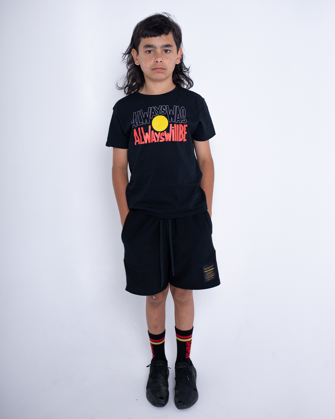 Clothing The Gaps. Black kids short sleeve T-shirt with Black, yellow and red 'always was always will be' text screen printed in centre.