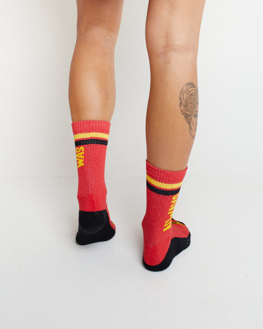 Clothing The Gaps. Power Socks 3 pack. 3 pack red, black and yellow thick cotton socks. Pair 1 Black base sock with 'Always was' on one side of sock and 'Always will be' on other side with red capital text and red and yellow band near top of sock. Pair 2 Red base sock with same text but in yellow and black. With yellow band near top of sock. Pair 3 yellow base sock with same text but in black. With black and red band near top of sock.