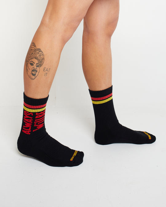 Clothing The Gaps. Power Socks 3 pack. 3 pack red, black and yellow thick cotton socks. Pair 1 Black base sock with 'Always was' on one side of sock and 'Always will be' on other side with red capital text and red and yellow band near top of sock. Pair 2 Red base sock with same text but in yellow and black. With yellow band near top of sock. Pair 3 yellow base sock with same text but in black. With black and red band near top of sock.