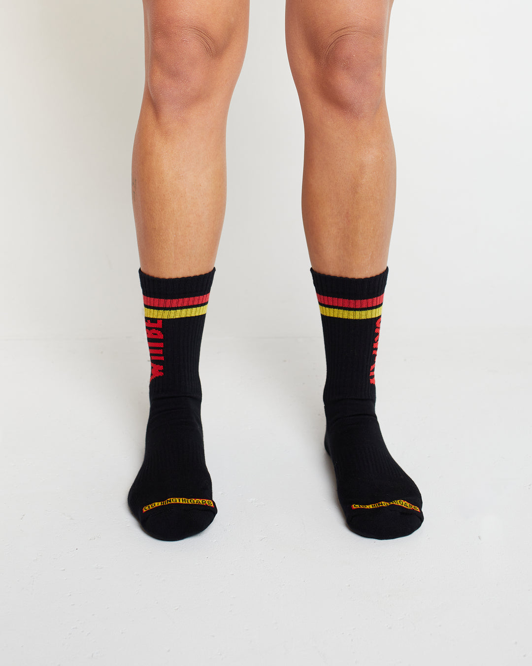 Clothing The Gaps. Power Socks 3 pack. 3 pack red, black and yellow thick cotton socks. Pair 1 Black base sock with 'Always was' on one side of sock and 'Always will be' on other side with red capital text and red and yellow band near top of sock. Pair 2 Red base sock with same text but in yellow and black. With yellow band near top of sock. Pair 3 yellow base sock with same text but in black. With black and red band near top of sock.