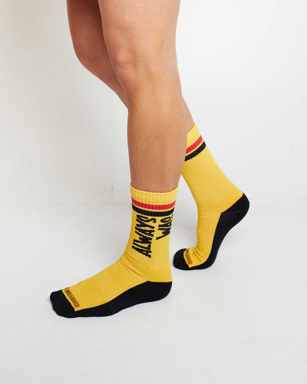 Clothing The Gaps. Power Socks 3 pack. 3 pack red, black and yellow thick cotton socks. Pair 1 Black base sock with 'Always was' on one side of sock and 'Always will be' on other side with red capital text and red and yellow band near top of sock. Pair 2 Red base sock with same text but in yellow and black. With yellow band near top of sock. Pair 3 yellow base sock with same text but in black. With black and red band near top of sock.